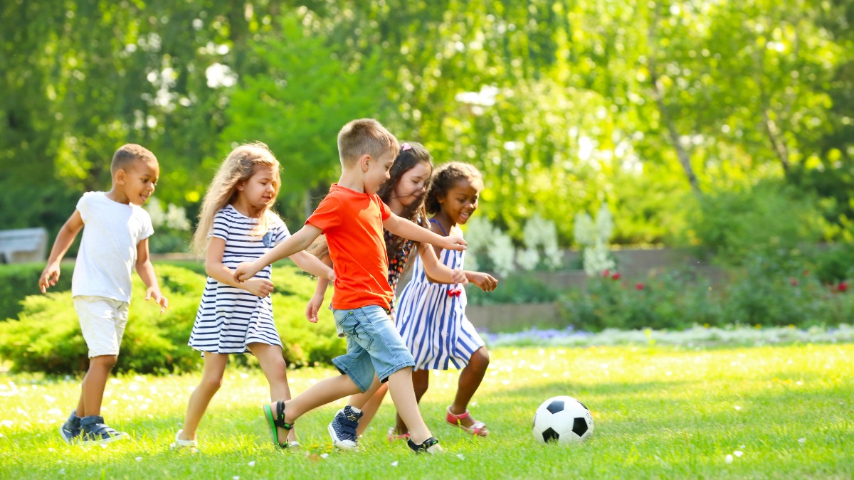 Niños y niñas jugando al fútbol en un espacio verde comunitario